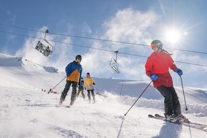 a group of people riding skis down a snow covered slope